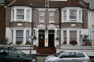 a house with two cars parked in front of it at Charlotte Guest House in London
