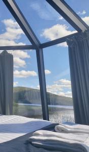 a bedroom with a large window with a view of a lake at Pyhän Asteli Aurora Igloos & Suites in Pyhätunturi