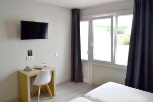 a room with a desk and a tv and a window at Alda Catedral in Santiago de Compostela