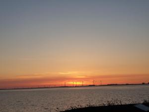 a sunset over the water with wind turbines in the distance at Johannes Hof in Bunde