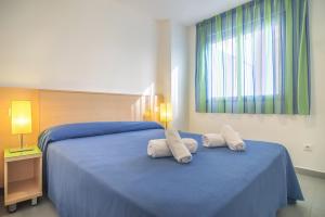 a bedroom with a blue bed with two white pillows at Apartamentos Hipocampos Calpe Rent Apart in Calpe
