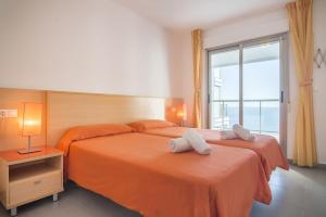 a bedroom with two beds with orange sheets and a window at Apartamentos Hipocampos Calpe Rent Apart in Calpe