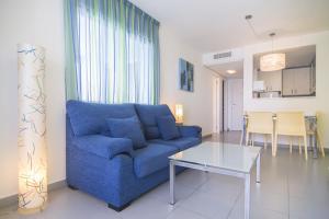 a living room with a blue couch and a table at Apartamentos Hipocampos Calpe Rent Apart in Calpe
