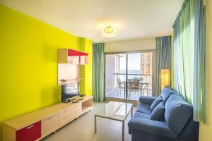 a living room with a blue couch and a tv at Apartamentos Hipocampos Calpe Rent Apart in Calpe