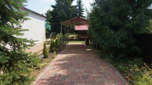 uma passarela de tijolos com um pavilhão num jardim em Sunny Apartman em Nyíregyháza