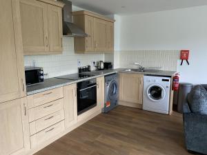 a kitchen with wooden cabinets and a washer and dryer at Toothbrush Apartments - Nr Train Station in Ipswich