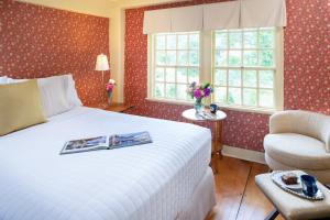a bedroom with a bed and a chair and windows at Waldo Emerson Inn in Kennebunkport