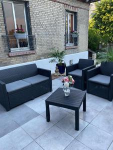 eine Terrasse mit Sofas und einem Tisch mit einer Blumenvase in der Unterkunft Villa avec maxi Jacuzzi aux Portes de Paris in Arcueil