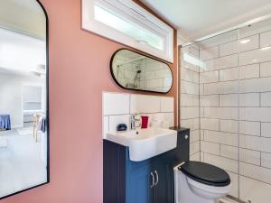 a bathroom with a sink and a toilet and a mirror at Pass the Keys The Beach Treehouse A Splendid Tranquil Retreat in Herne Bay