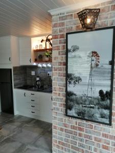 a kitchen with a brick wall with a picture of a windmill at Just Chill Betty's Bay in Bettyʼs Bay
