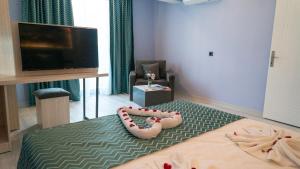 Zimmer mit einem Bett, einem TV und einem Paar Hausschuhen. in der Unterkunft Livaneli Boutique Otel in Alanya