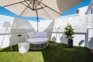 - un balcon avec une chaise et un parasol dans l'établissement Magno Apartments Alameda 1851 Penthouse - Private terrace and jacuzzi, à Séville