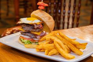 a plate with a hamburger and french fries on a table at BON Hotel Bloemfontein Central in Bloemfontein