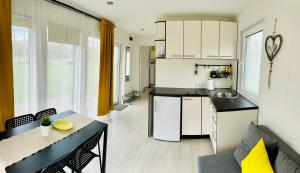 a kitchen with white cabinets and a table and a dining room at Teitupes, brīvdienu mājas pie jūras in Ķesterciems