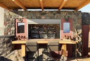 un bar dans un mur en pierre avec deux tables et des chaises dans l'établissement White Pearl Cavalieri, à Imerovigli