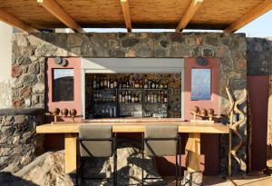 a bar in a stone wall with two tables and chairs at White Pearl Cavalieri in Imerovigli