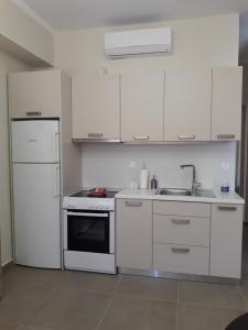 a kitchen with white cabinets and a sink and a refrigerator at Plakoures Home in Kounoupidhianá