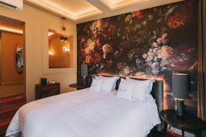 a bedroom with a large white bed with a painting on the wall at The Felix 10 in Lisbon