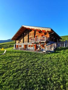 a large log cabin in a field of grass at Chambres et Tables d'Hôtes Le Choton à Nono - Col du Joly Beaufortain in Hauteluce