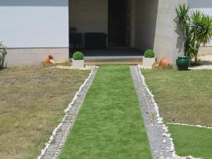 a garden with grass and rocks in front of a house at Buarcos Luxury Guest house in Figueira da Foz