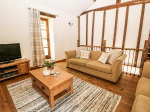 a living room with a couch and a tv at The Barn in Buxton
