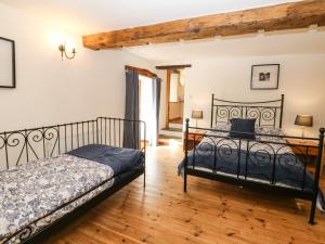 een slaapkamer met 2 bedden en een houten vloer bij The Barn in Buxton