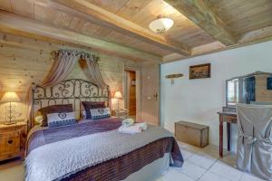 een slaapkamer met een groot bed met een houten plafond bij Chalet Cœur de Marie avec sauna et jacuzzi - Val d'Arly in Flumet