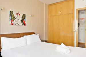 バルセロナにあるStay U-nique Apartments Bonsomsの白いベッドと木製キャビネット付きのベッドルーム1室が備わります。