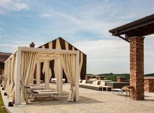 un pavillon avec des chaises et des tables ainsi qu'un bâtiment en briques dans l'établissement Montalbera Wine Suites, à Montemagno