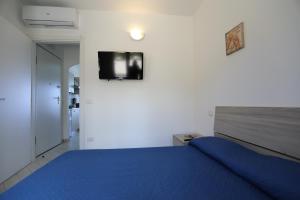 sypialnia z niebieskim łóżkiem i telewizorem na ścianie w obiekcie Isola Rossa Elite w mieście Trinità dʼAgultu