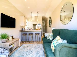 a living room with a green couch and a kitchen at Raffinbow Retreat in Mickleton