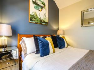 a bedroom with a bed with blue and yellow pillows at Raffinbow Retreat in Mickleton