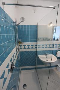 W wyłożonej niebieskimi kafelkami łazience znajduje się umywalka i prysznic. w obiekcie Isola Rossa Elite w mieście Trinità dʼAgultu