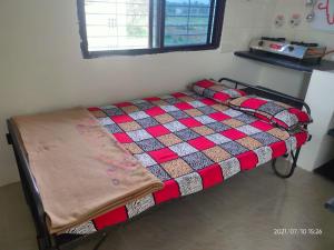 a bed with a quilt on it in a room at Akshay Sweet Home Stay in Mysore