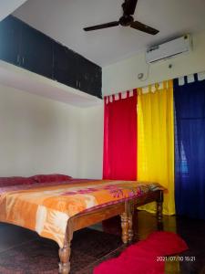 邁索爾的住宿－Akshay Sweet Home Stay，一间多彩的窗帘和一张床上的房间