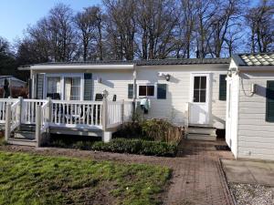 een wit huis met een veranda en een hek bij Heidepark Veluwschkarakter in Vierhouten