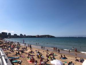 a crowd of people on a beach with the ocean at Casa en la playa in Gijón