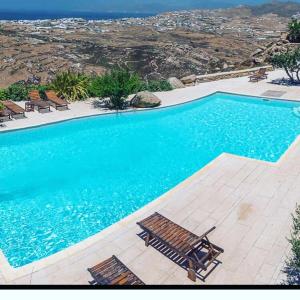 a large swimming pool with two chairs and a bench at Luxury Sunset in Mikonos