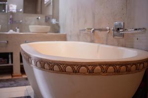 a white tub in a bathroom with a sink at If Not Why Not Guesthouse in Potchefstroom