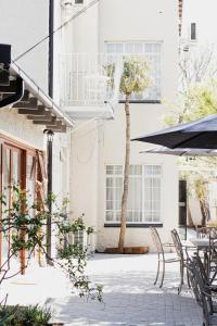 a patio with chairs and a tree in front of a building at If Not Why Not Guesthouse in Potchefstroom
