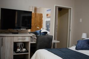 a bedroom with a bed and a desk with a television at If Not Why Not Guesthouse in Potchefstroom