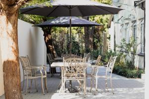 a table and chairs with an umbrella on a patio at If Not Why Not Guesthouse in Potchefstroom