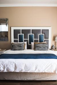 a large bed with blue and white pillows on it at If Not Why Not Guesthouse in Potchefstroom