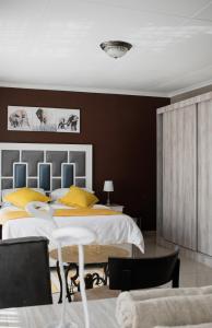 a bedroom with a large bed with yellow pillows at If Not Why Not Guesthouse in Potchefstroom