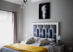 a bedroom with a large bed with a yellow blanket at If Not Why Not Guesthouse in Potchefstroom