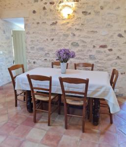 a table with chairs and a vase of flowers on it at La Croix du Sud - Ocres en Provence in Apt
