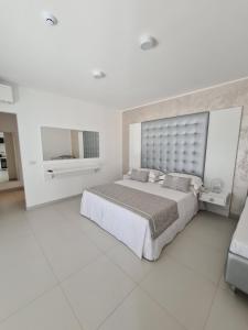 a white bedroom with a large bed and a mirror at Baia del Sole Vasto in Vasto