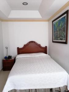 a bedroom with a bed with a wooden headboard at Hotel Bolivar Plaza in Manizales
