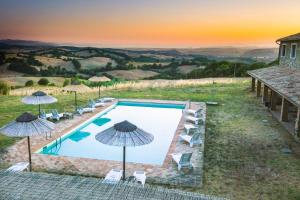 a pool with chairs and umbrellas on a hill at Le Murelle Country Resort in Manciano