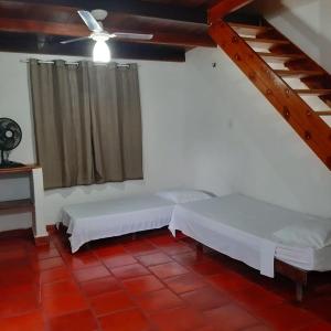 a room with two beds and a ceiling fan at Pousada Morada do Sol in Canoa Quebrada